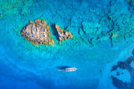 Aerial view of beautiful yacht on the sea and rocks at sunset, a Nature Photo by den-belitsky