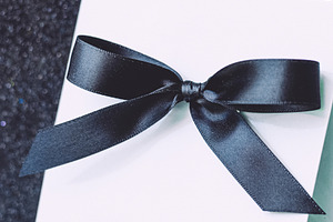 Minimalist white gift or invitation card with elegant black ribb, a Photo by Studio ANNA
