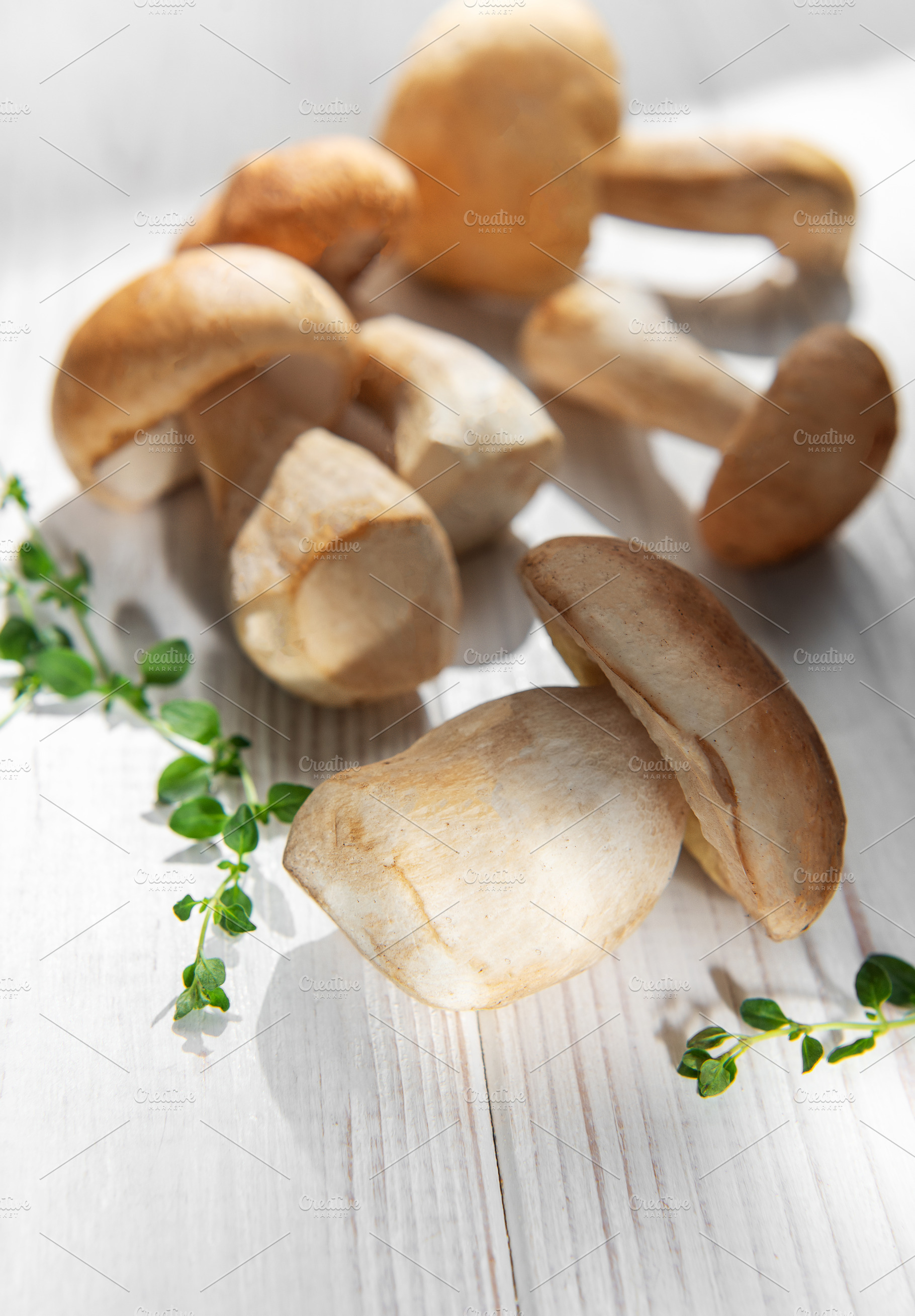 Porcini mushrooms with thyme on white wood background, a Food & Drink Photo by Olena Rudo