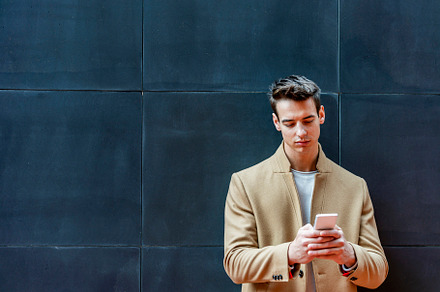 Businessman texting on mobile phone against wall, a Person Photo by RF Images