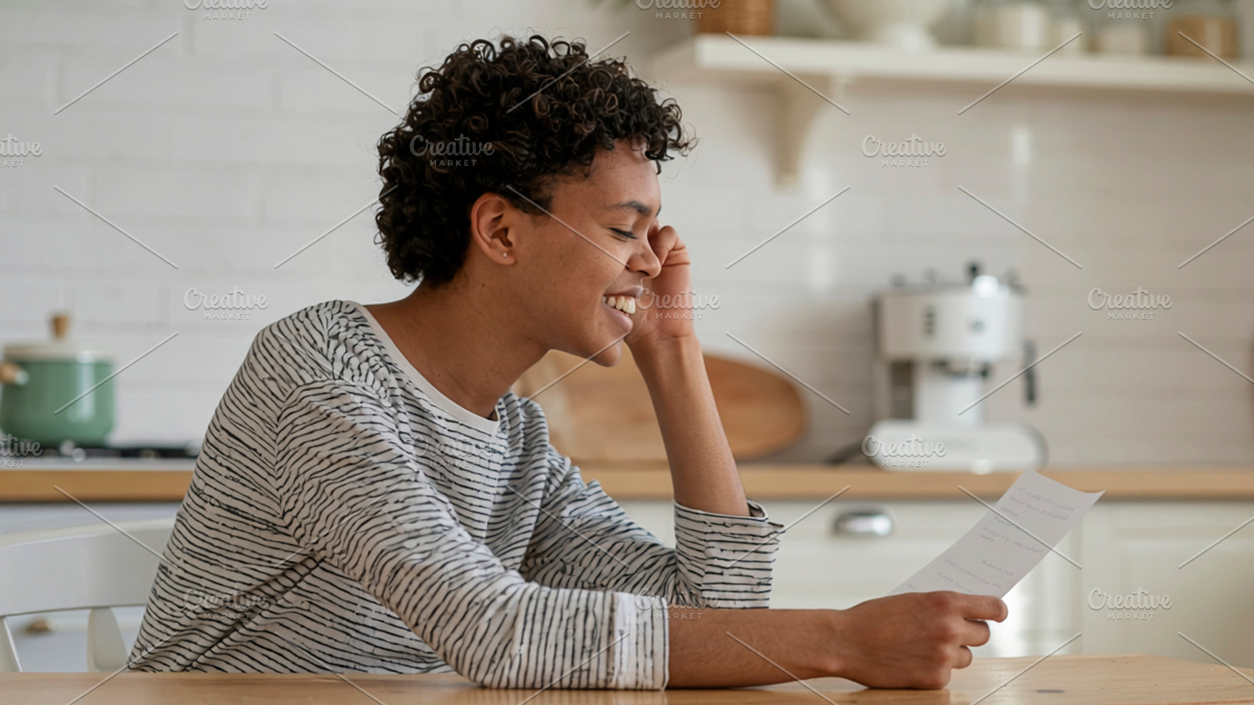 Smiling person holding paper at kitchen counter, a Photo by DanFLCreativo
