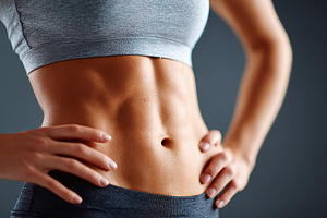 Fit young woman showcases toned abs in studio setting while posing confidently, a Sports & Recreation Photo by AlyaAnd