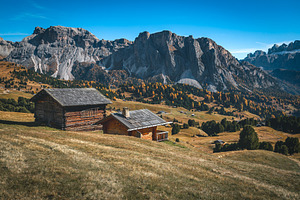 Log houses on the slope in the Alps, a Nature Photo by Alpine Dreams