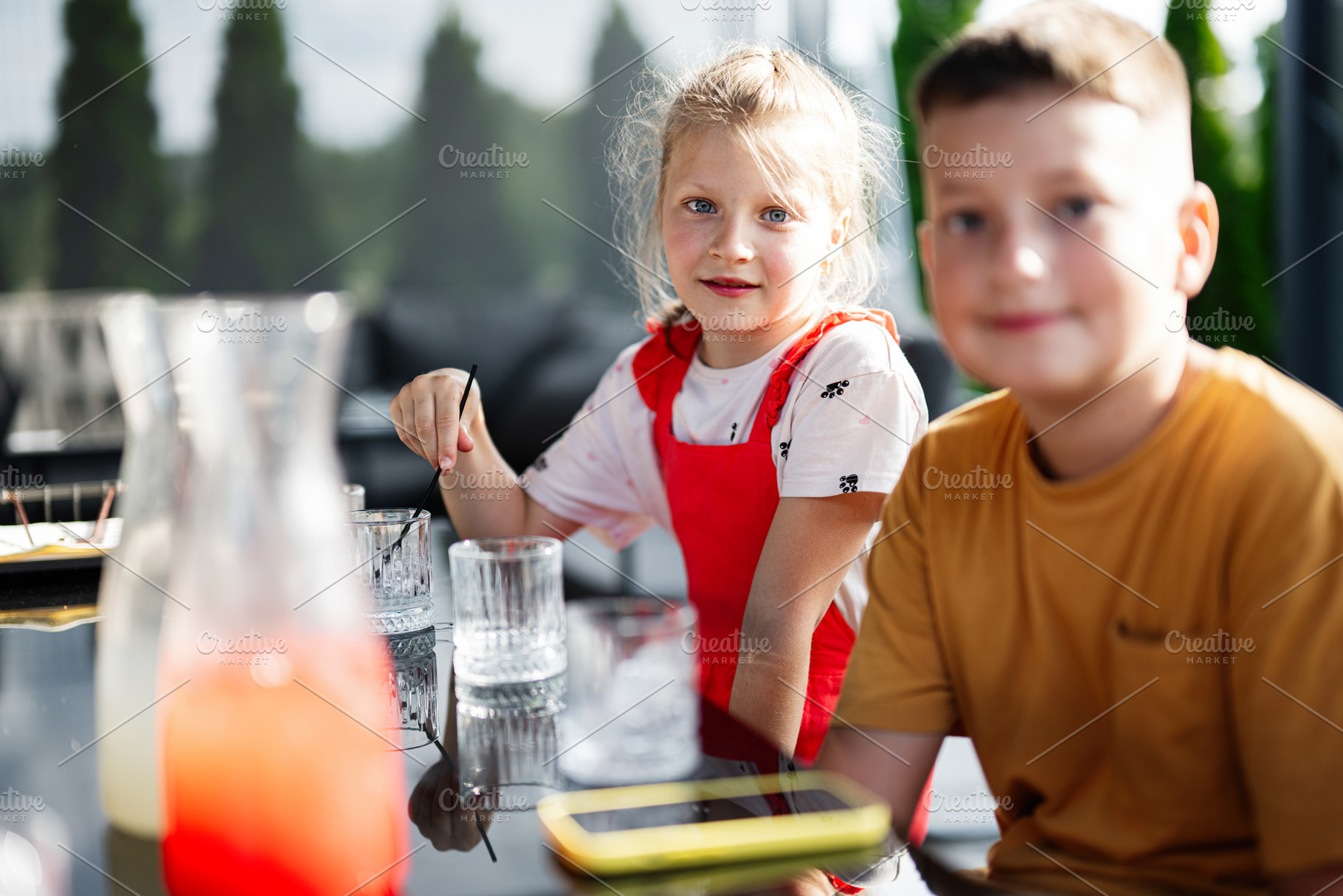 Two children enjoying a sunny outdoor meal at a table, a Photo by AS photostudio
