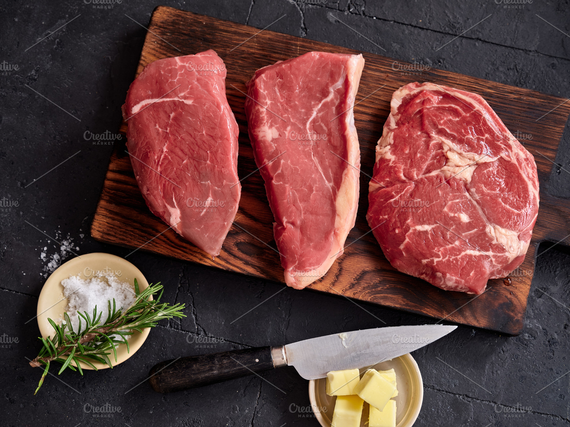 Raw rib-eye, roast beef, flank and rump steak on a wooden board with knife and, a Food & Drink Photo by Asya Nurullina