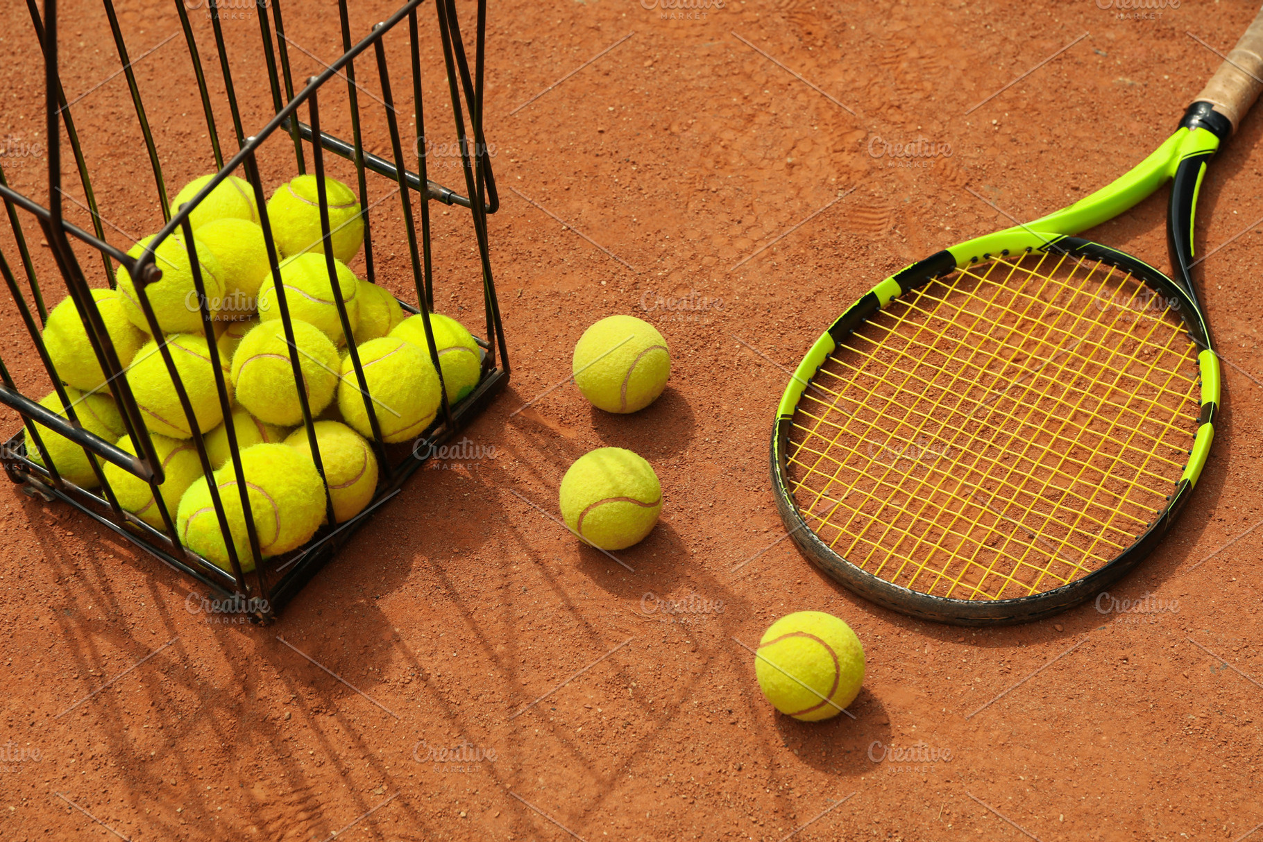 Racket and basket with tennis balls on clay court, a Sports ...