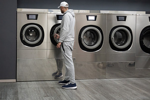 Man Using Self-Service Washing Machine in Modern Laundromat, a Person Photo by etorres69
