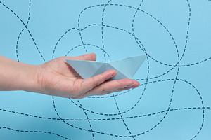 A person holding a paper boat on their palm against a background, a Business Photo by ndanko