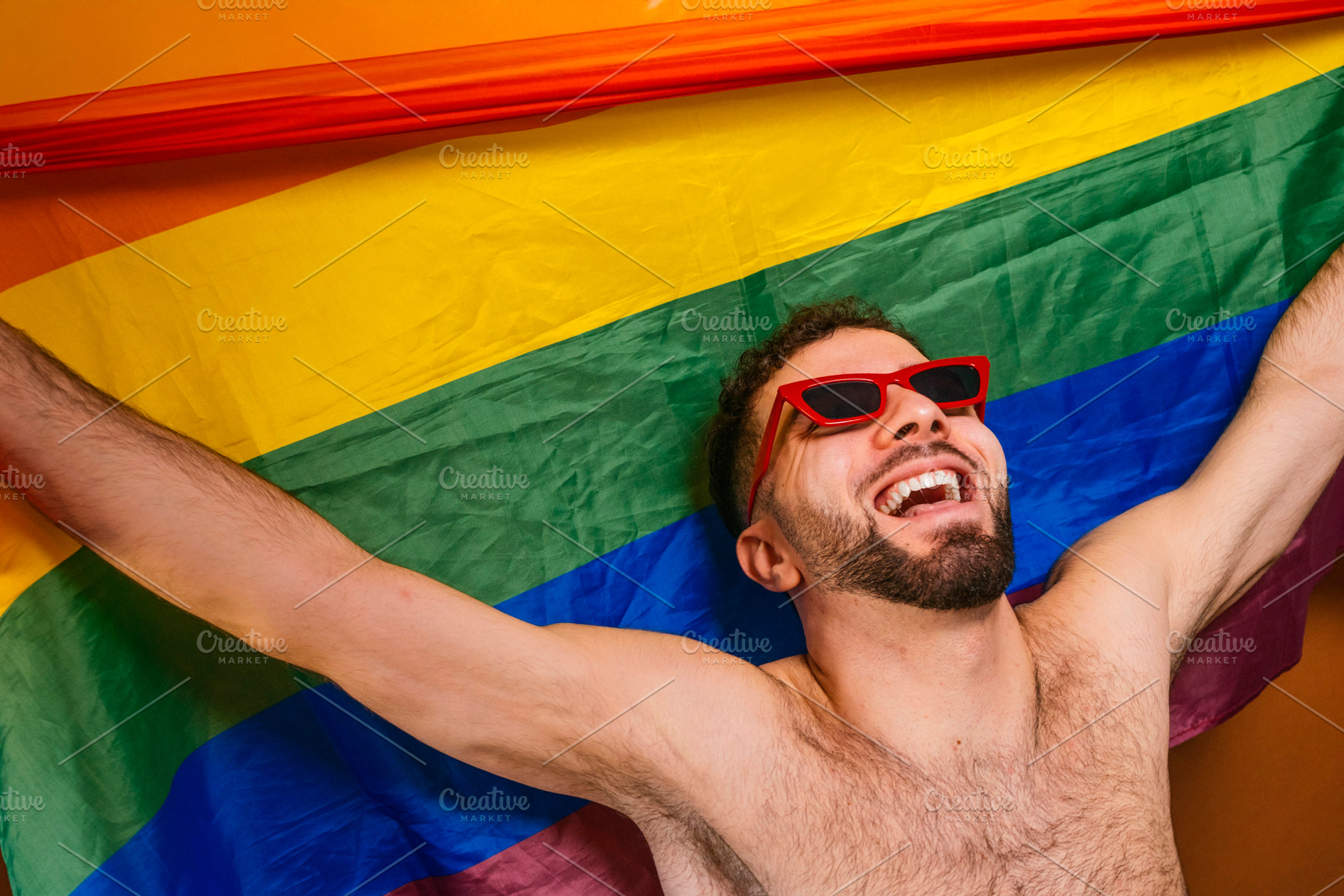 Young man celebrating pride month with rainbow flag, a Photo by karrastock