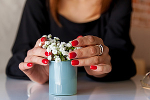Womans hands with red nails holding small flower vase, a Person Photo by Photostock