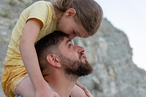 Young girl and her father share a tender moment outdoors, embracing affection a, a Person Photo by Ales Munt