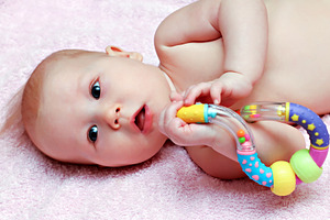 Newborn baby playing with colorful rattle, a Photo by saiko3p