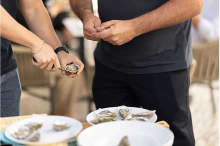 Two men open oysters with a knife at, a Food & Drink Photo by Barcelona_dreams