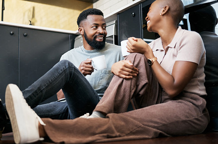 Relax, talking and an African couple with coffee on the kitchen floor in the morning. Love, happy and black man and woman drinking a cup of tea, latte or warm beverage with conversation together, a Photo by Peopleimages.com