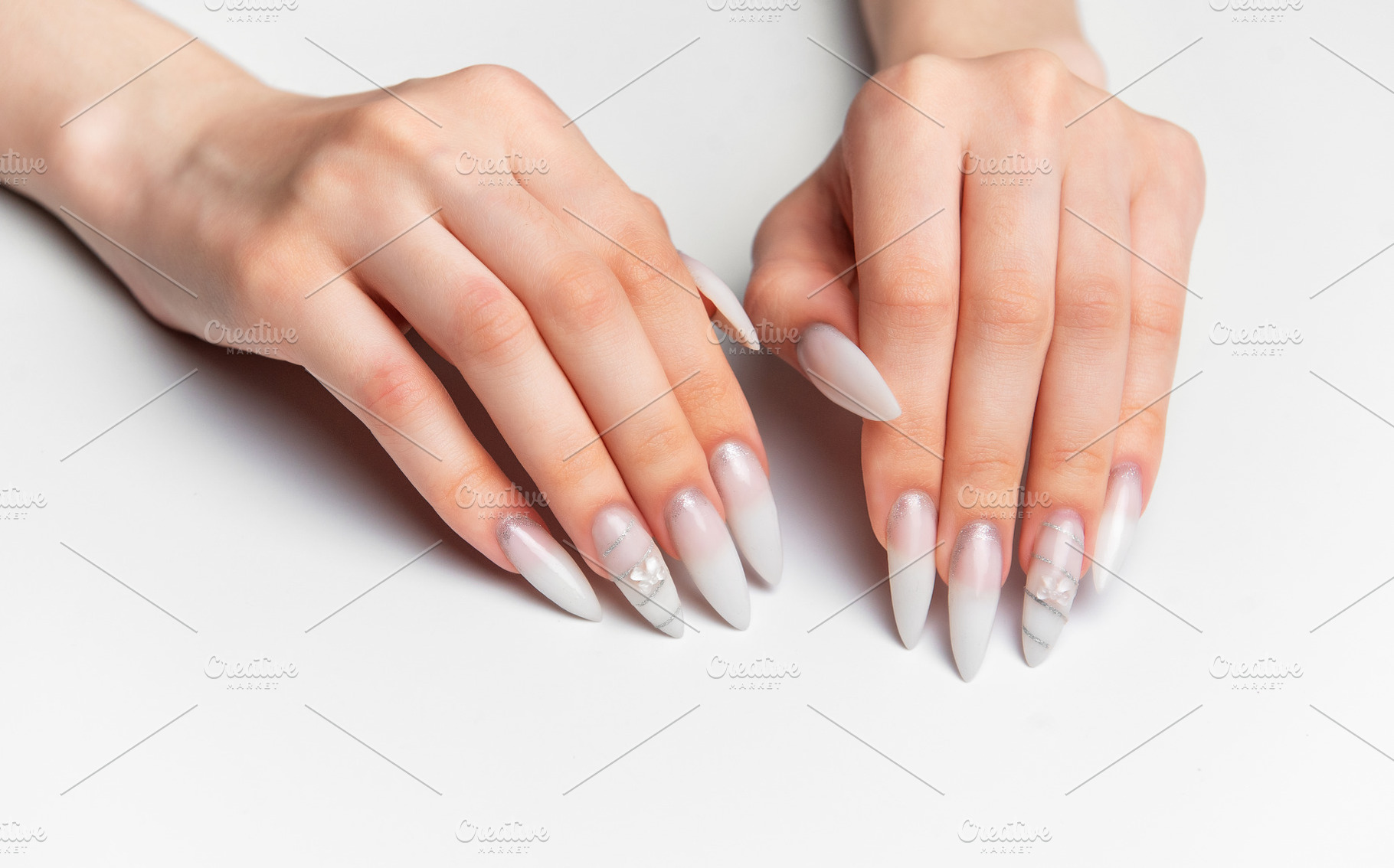 Woman's hands showing long white almond shape nails with art, a Photo by Olena Rudo