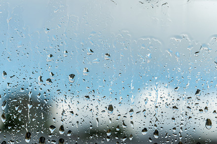 Raindrops on a window with a blue cloudy sky in the background., an Abstract Photo by Eugene_Photo