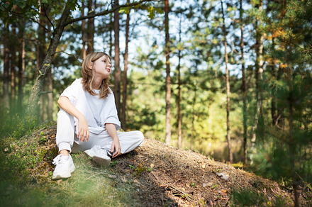 Young girl enjoying a sunny day in a forest clearing while sitti, a Person Photo by Olena Rudo