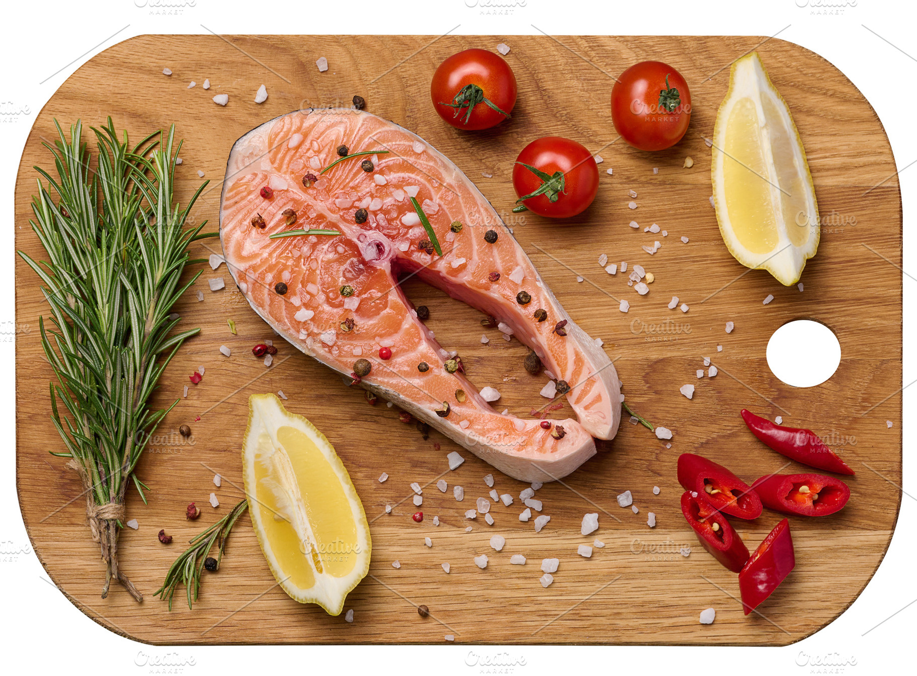 Raw salmon steak on a wooden cutting board, lemon slices, spices, a Food & Drink Photo by ndanko