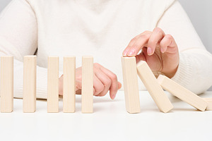 Woman's hand stopping falling wooden blocks, preventing the domi, a Person Photo by ndanko