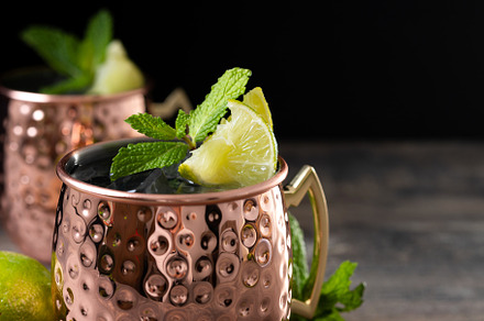 Moscow mule cocktail served with ice and lime slice on wooden table, a Food & Drink Photo by etorres69