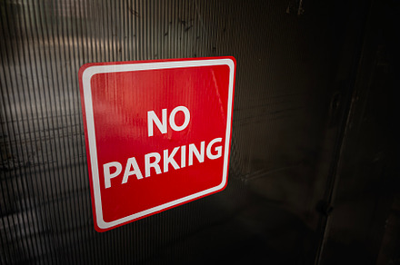 Red and white no parking sign displayed on a dark textured surface, a Photo by AS photostudio