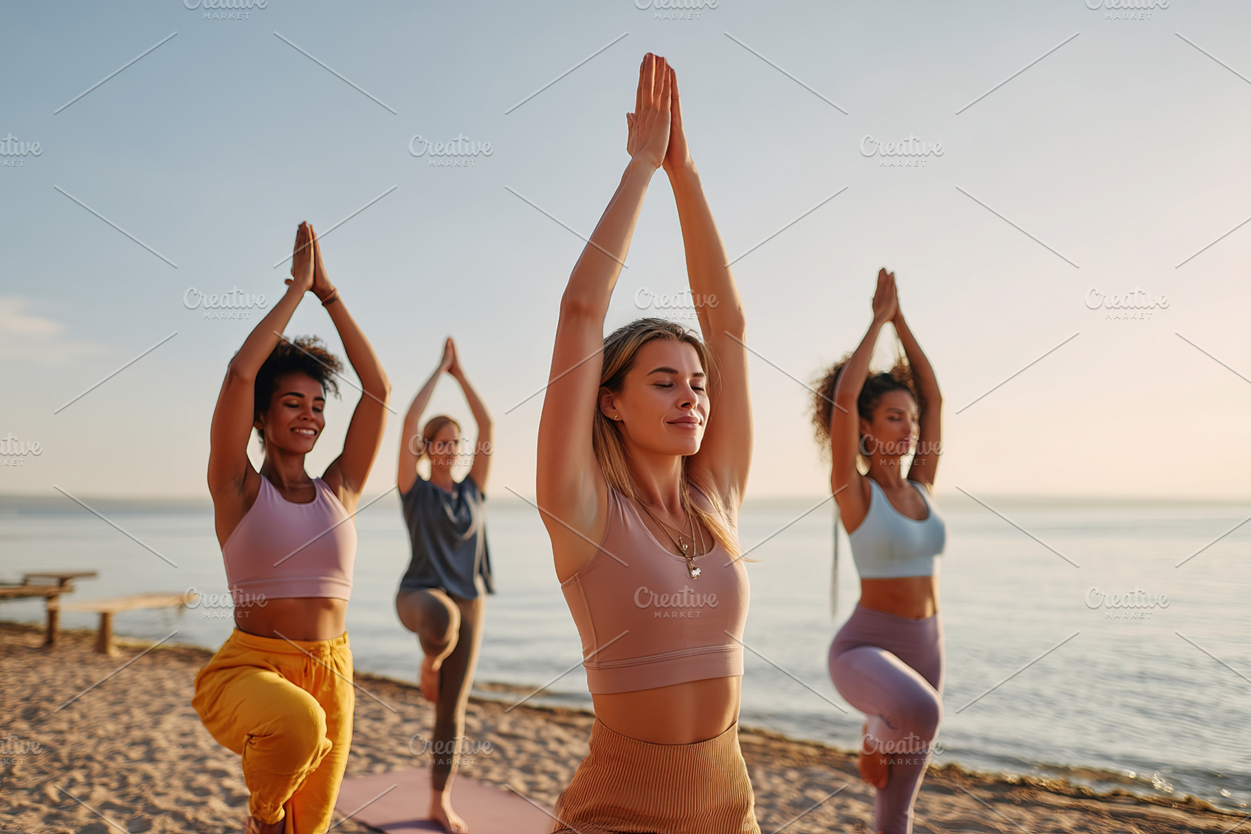 Women in yoga practice on mats along a tranquil beach, a Sports & Recreation Photo by AlyaAnd