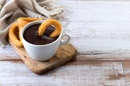 Traditional Spanish churros with hot chocolate breakfast on wooden table. Copy, a Food & Drink Photo by etorres69