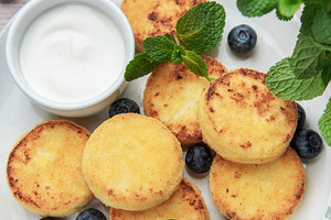 Syrniki pancakes with blueberries, sour cream, and honey, a Food & Drink Photo by Olena Rudo
