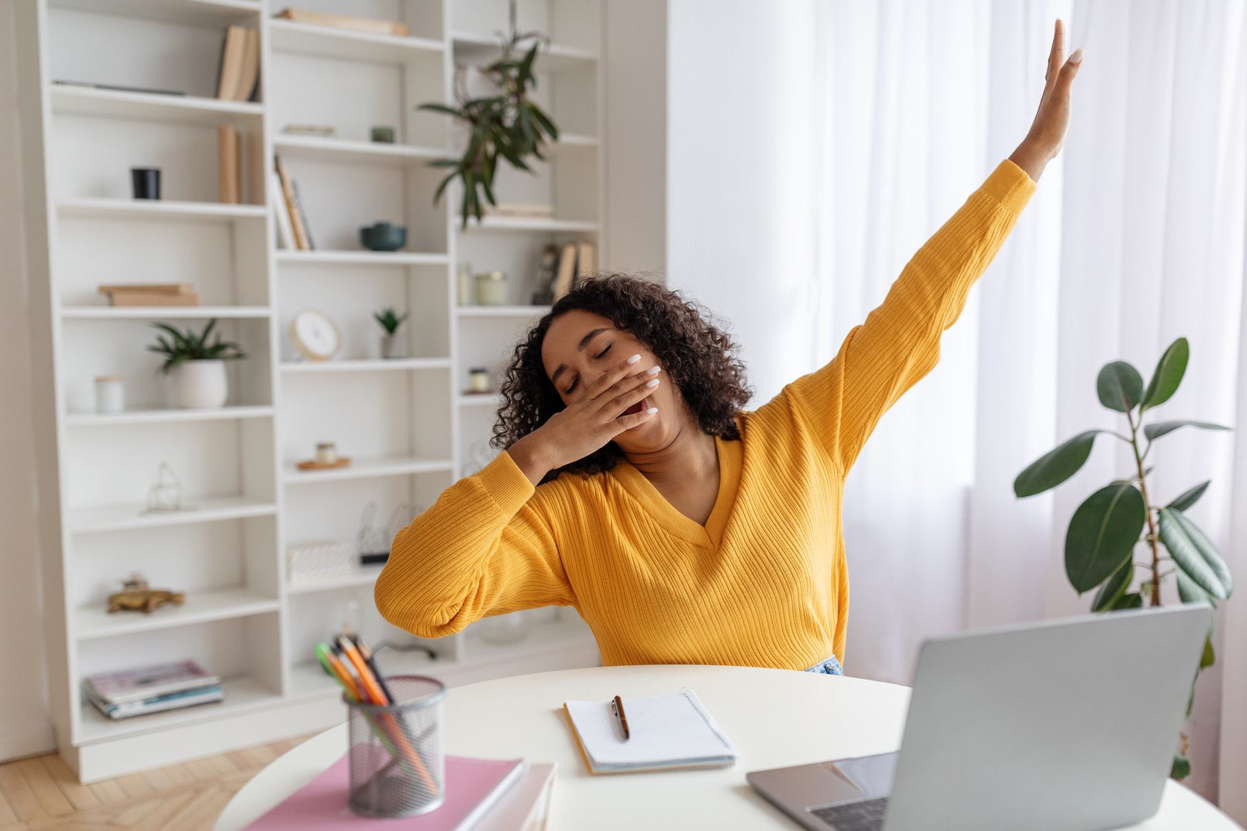 Tired young black female student yawning in front of laptop during ...