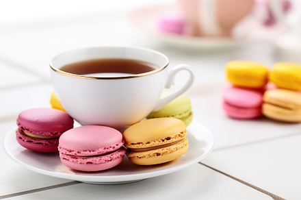 Colorful macarons with cup of tea on wooden background, a Food & Drink Photo by AlyaAnd