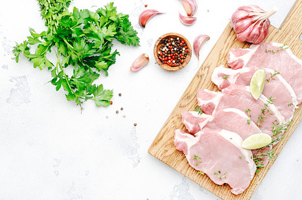 Raw pork chops, meat on cutting board prepared for cooking with, a Food & Drink Photo by 5PH