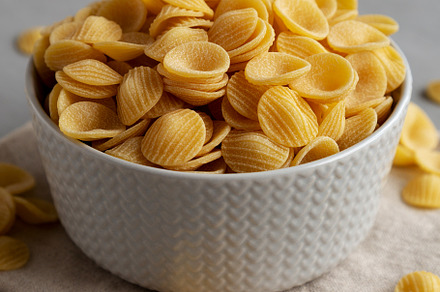 Dry, Uncooked Orecchiette Pasta in a Bowl, side view. Close-up., a Food & Drink Photo by LiudmylaChuhunova