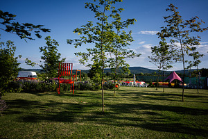 Outdoor park landscape with red art chair, green grass, and vibrant scenery, a Photo by AS photostudio