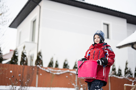 Boy hold bucket with snow against house in winter. Active outdoo, a Person Photo by AS photostudio