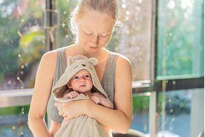 Mother holding her baby in a bath, a Person Photo by Elizaveta Galitskaya