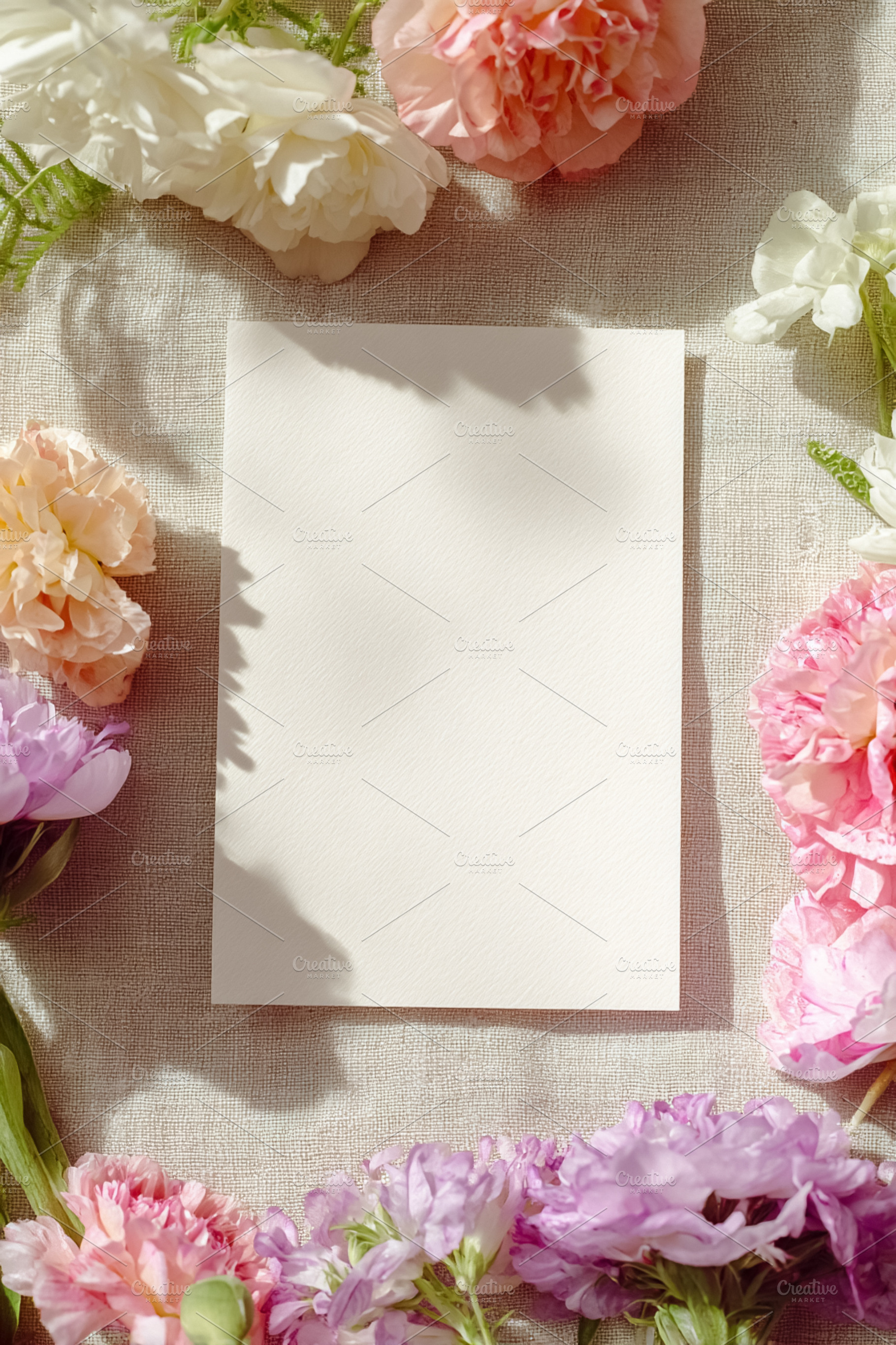 Blank paper card mock up resting on linen fabric with colorful p, a Photo by Studio ANNA