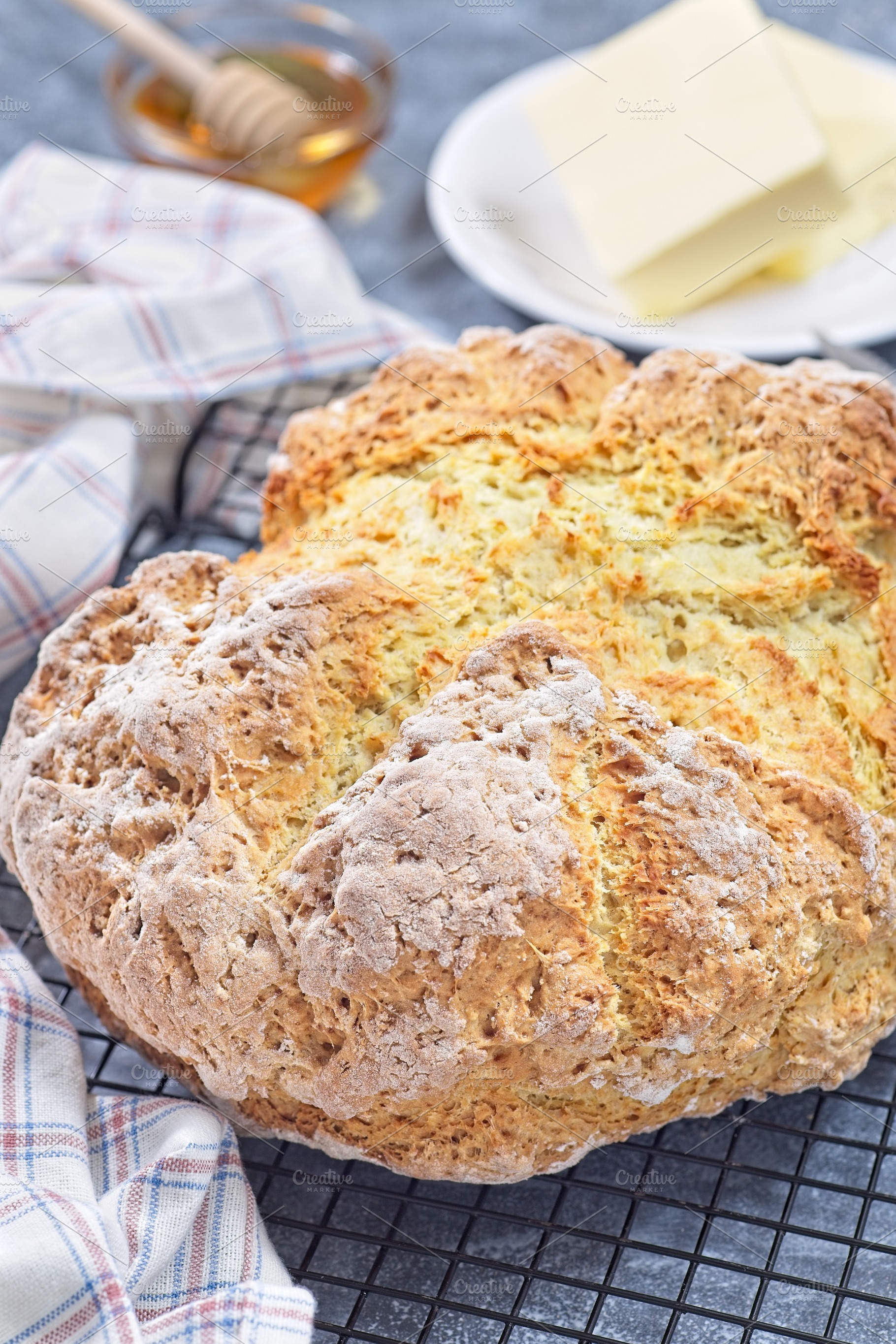 Freshly baked soda bread on cooling rack with butter and honey in the backgroun, a Food & Drink Photo by iuliia_n