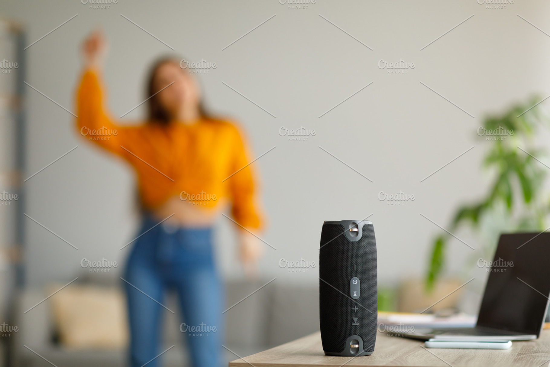 Young lady dancing to popular music at home, selective focus on portable wirele, a Photo by Prostock-Studio