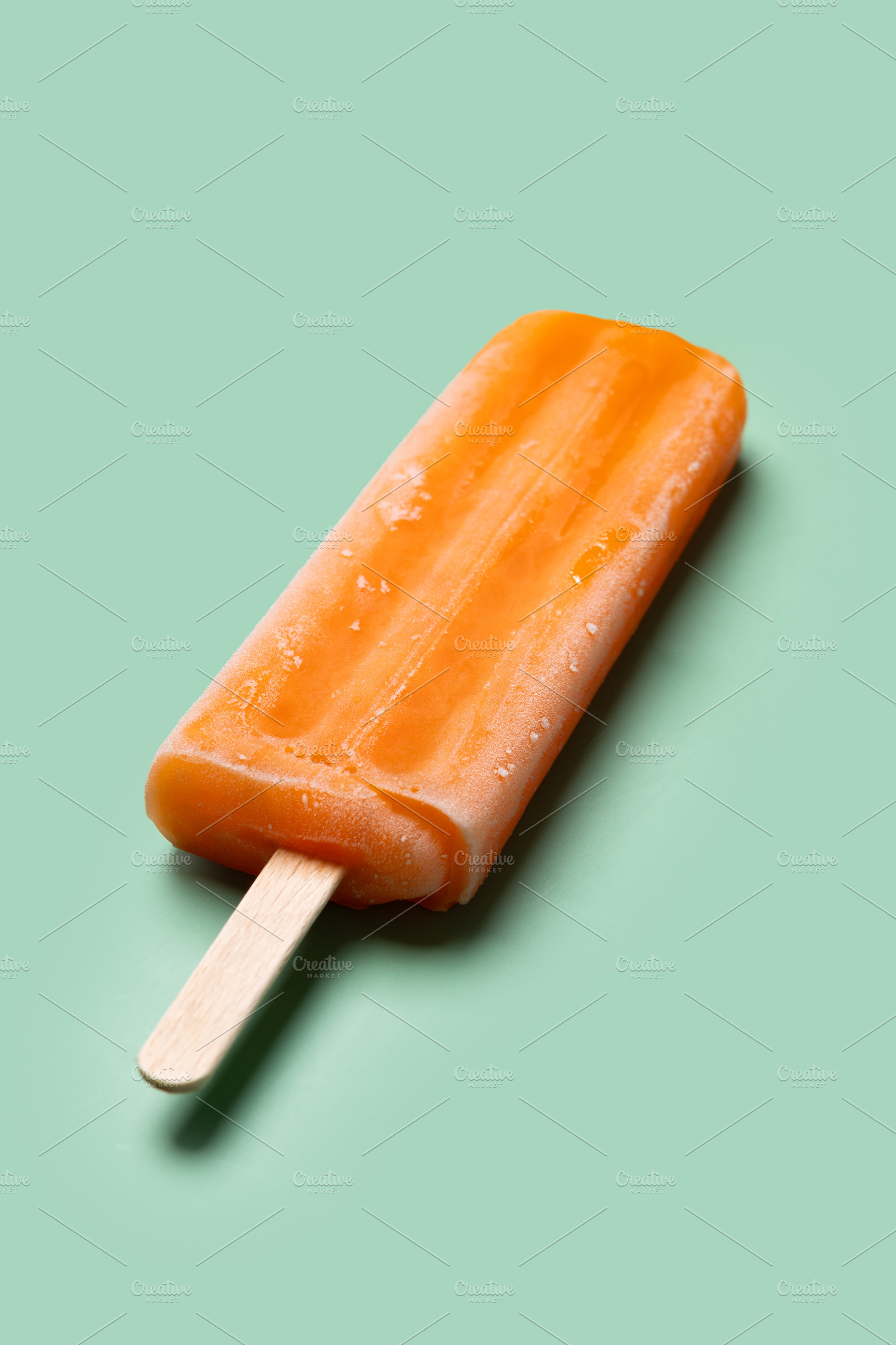 Orange popsicle on green background, a Food & Drink Photo by etorres69