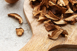 Dried mushrooms on wooden cutting board with fresh mushrooms, a Food & Drink Photo by Olena Rudo