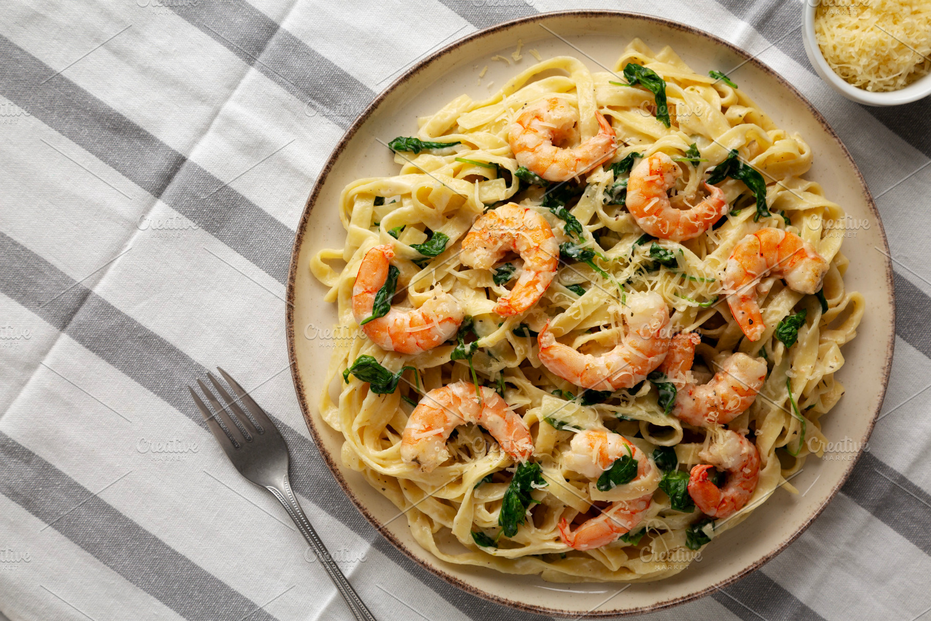 Homemade Creamy One-Pot Spinach Shrimp Pasta on a Plate, top vie, a Food & Drink Photo by LiudmylaChuhunova