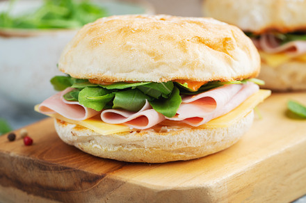 Two homemade sandwiches with ham, cheese and arugula on a concrete table., a Food & Drink Photo by Budarinphoto