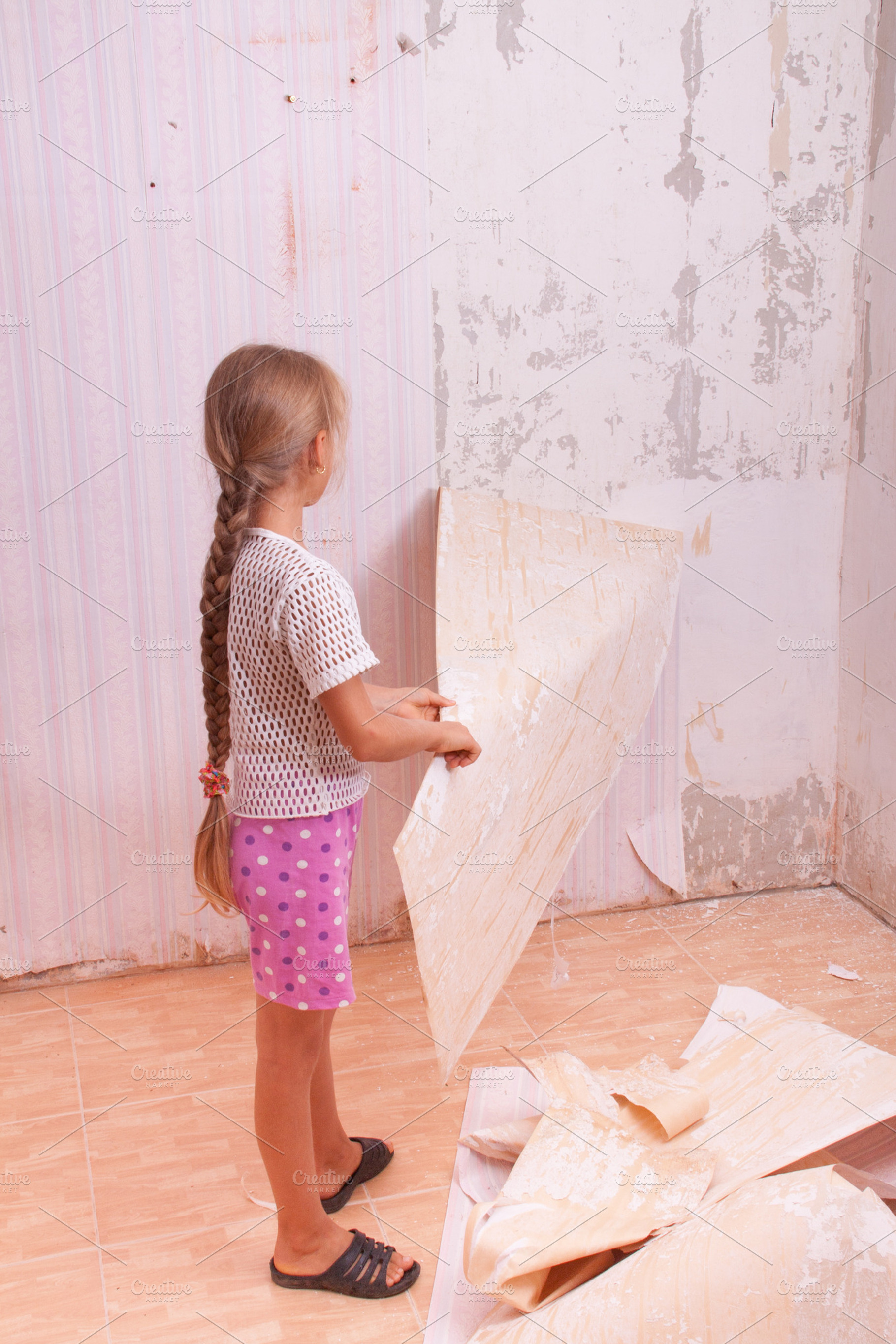 girl remove old wallpapers from wall, a Wallpaper Photo by NataPhoto