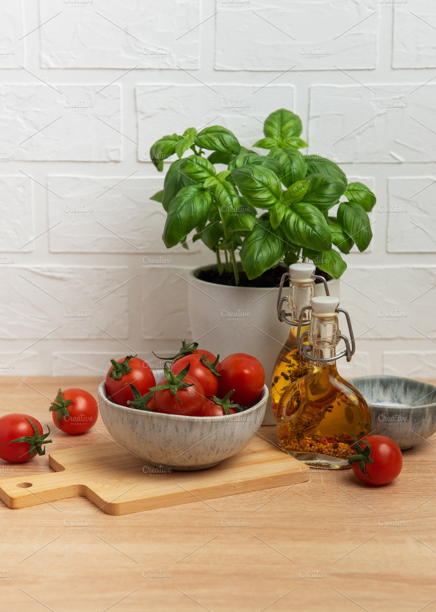Cherry tomatoes and basil with olive oil on kitchen table, a Food & Drink Photo by Olena Rudo