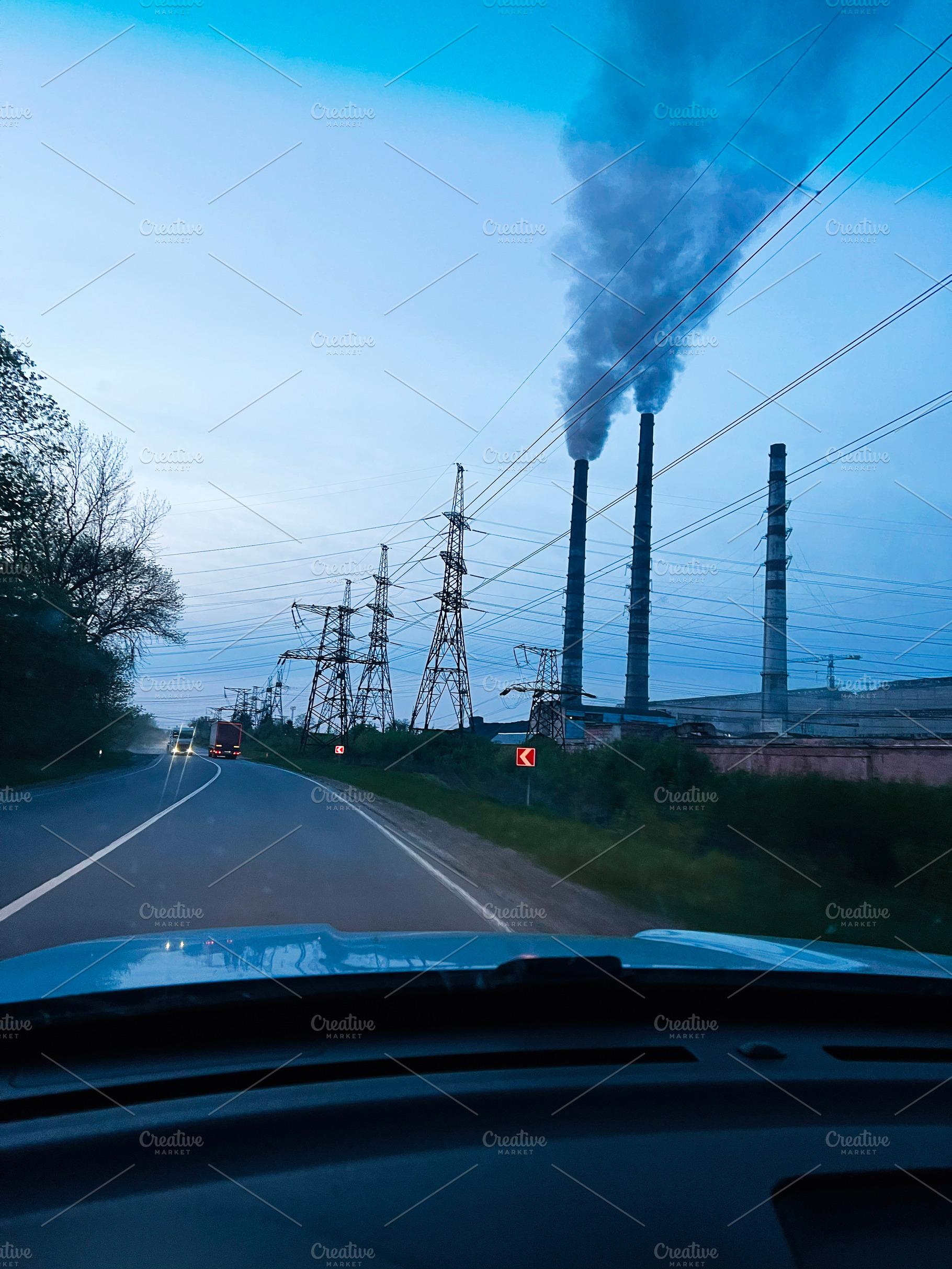Industrial TPP smokestacks emitting smoke near power lines along a rural road, a Photo by AS photostudio