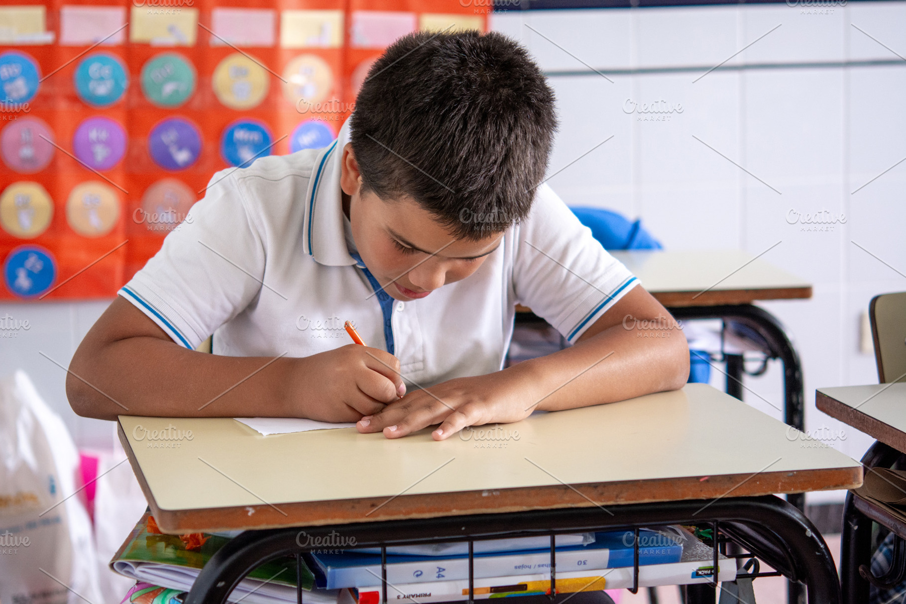 Focused Elementary School Student Writing at Desk During Classroom Activity, a School & Education Photo by etorres69