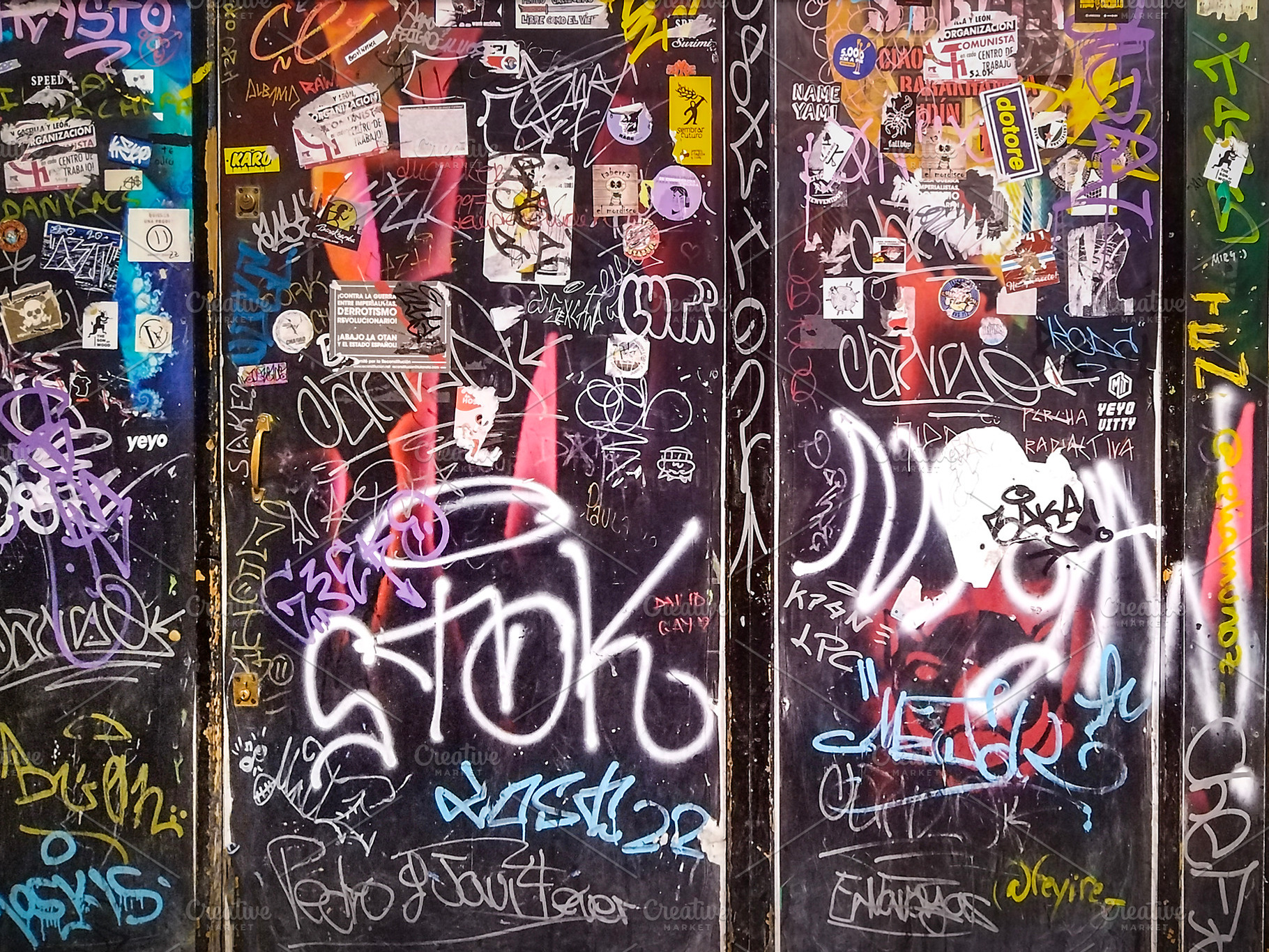Graffiti-covered metal doors with urban stickers, an Abstract Photo by DanFLCreativo