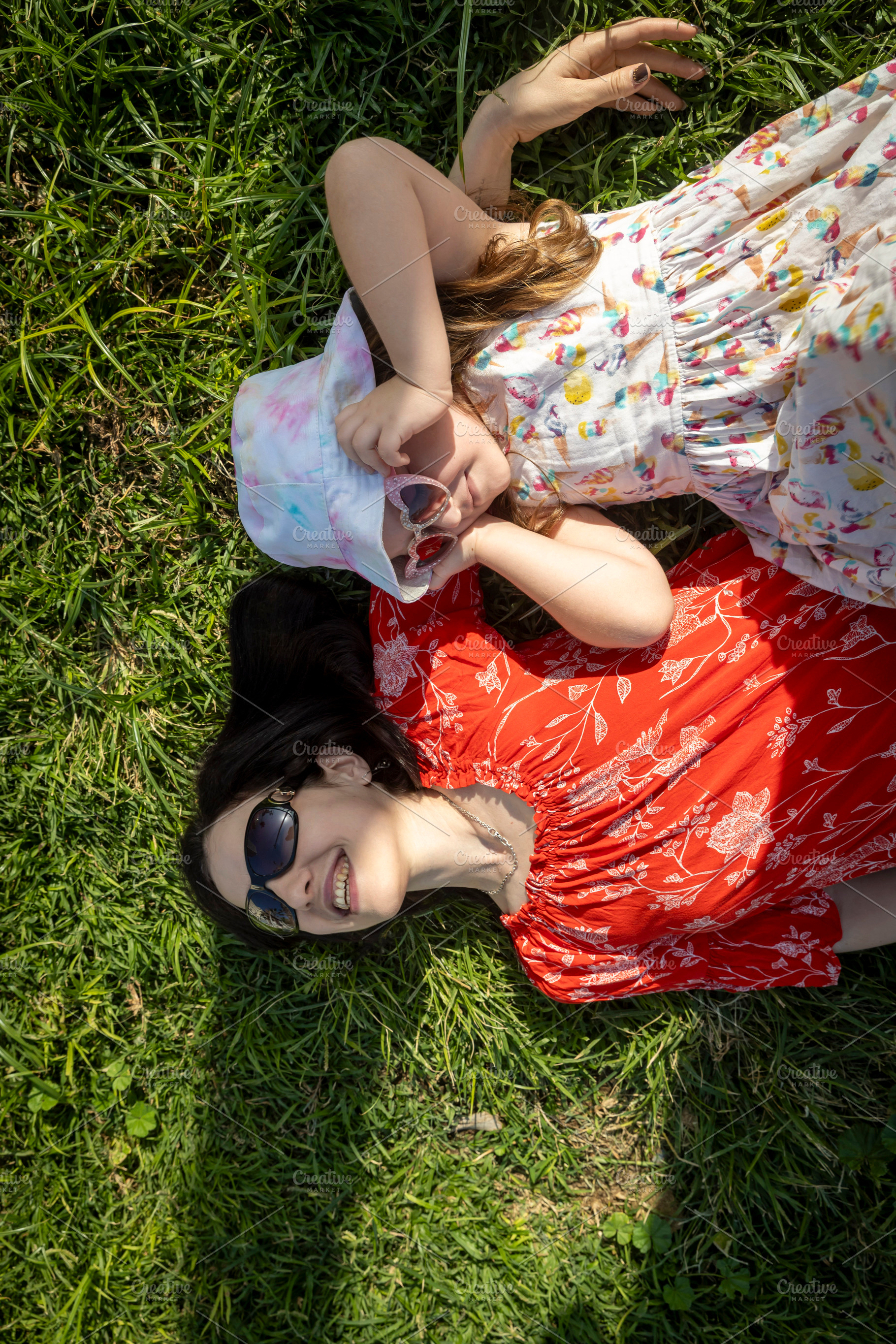 Top view of a mother and daughter lying on green grass, smiling, a Person Photo by Imaginarium