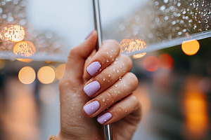 Hand holding umbrella with lavender nails during rainy evening in the city, a Beauty & Fashion Photo by AlyaAnd
