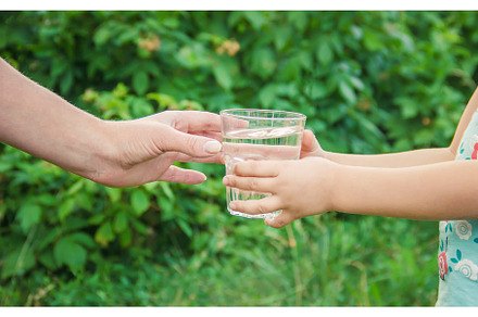 The father gives the child a glass, a Food & Drink Photo by yanadjana